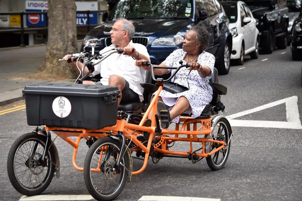A man and a woman ride together on a side-by-side bicycle